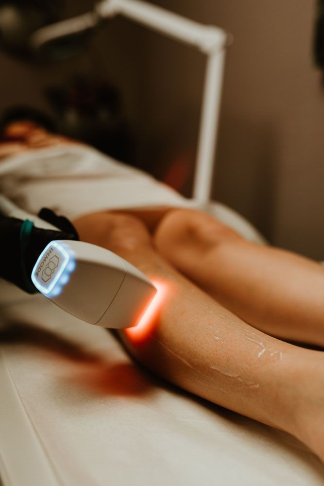 A woman is getting a laser hair removal treatment on her legs.