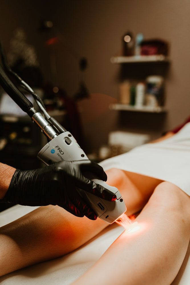 A woman is getting a laser hair removal treatment on her legs.