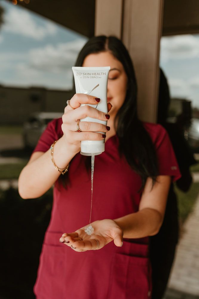 A woman is holding a bottle of lotion in her hand.