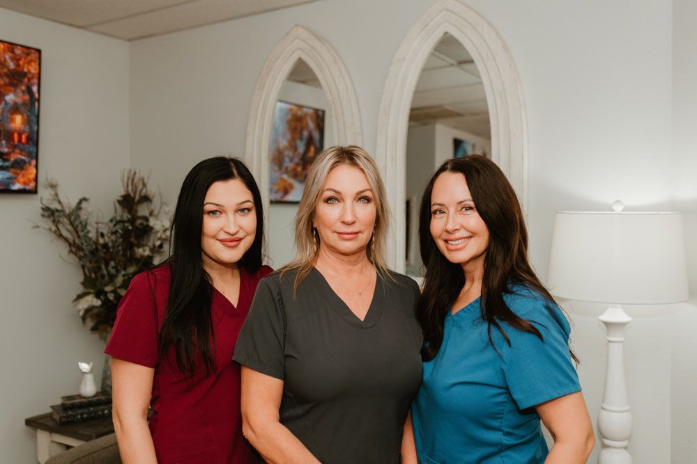 Three women in scrubs are posing for a picture in a room.