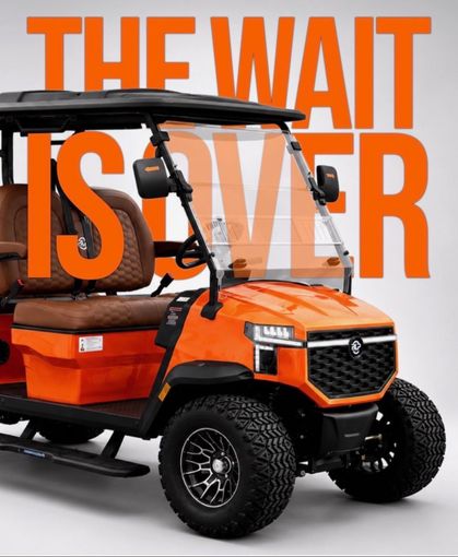 Orange utility golf cart with cargo bed and large tires, overlaid with text “THE WAIT IS OVER”