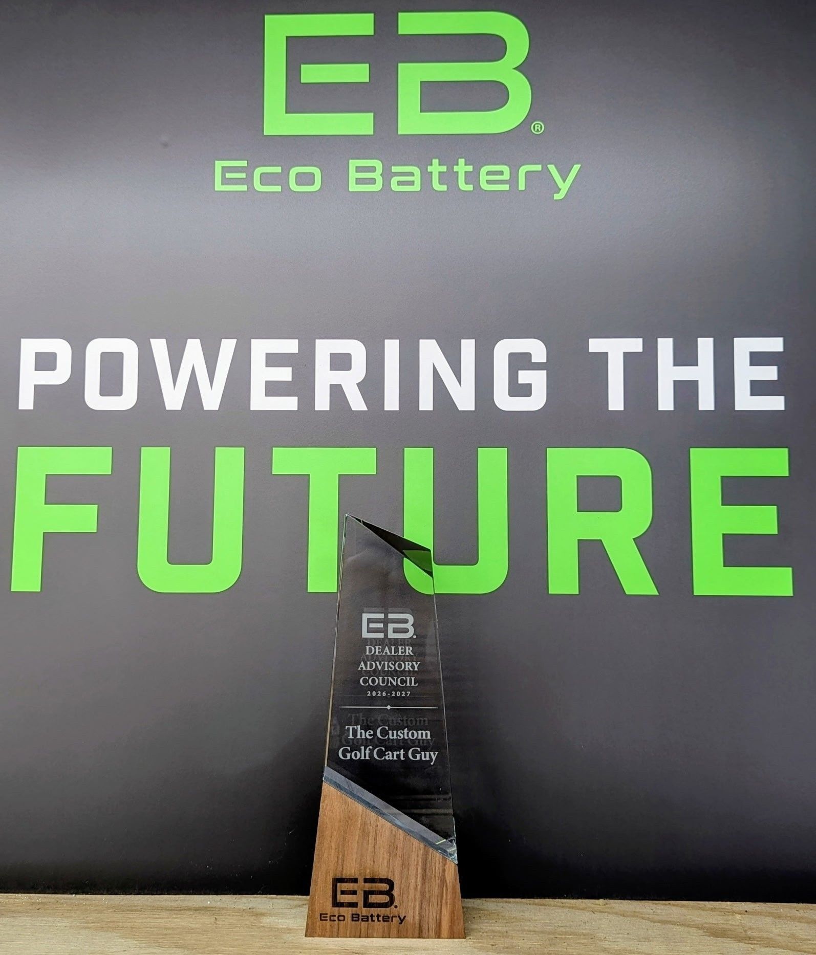 Eco Battery trophy display with “Powering the Future” slogan on a black and green backdrop