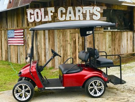 A red golf cart is parked in front of a sign that says golf carts