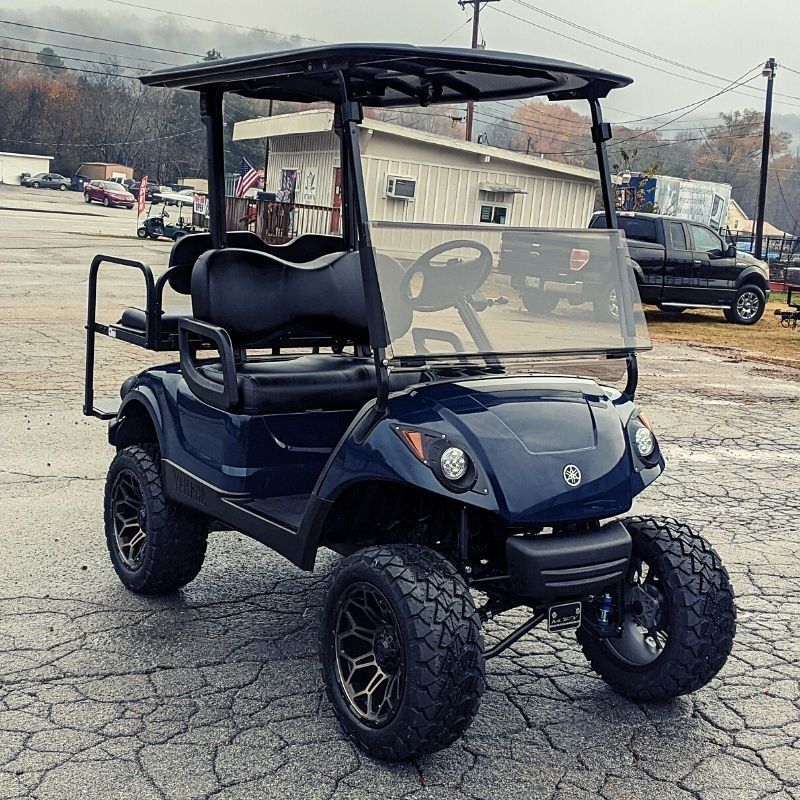 A blue golf cart is parked in a parking lot.
