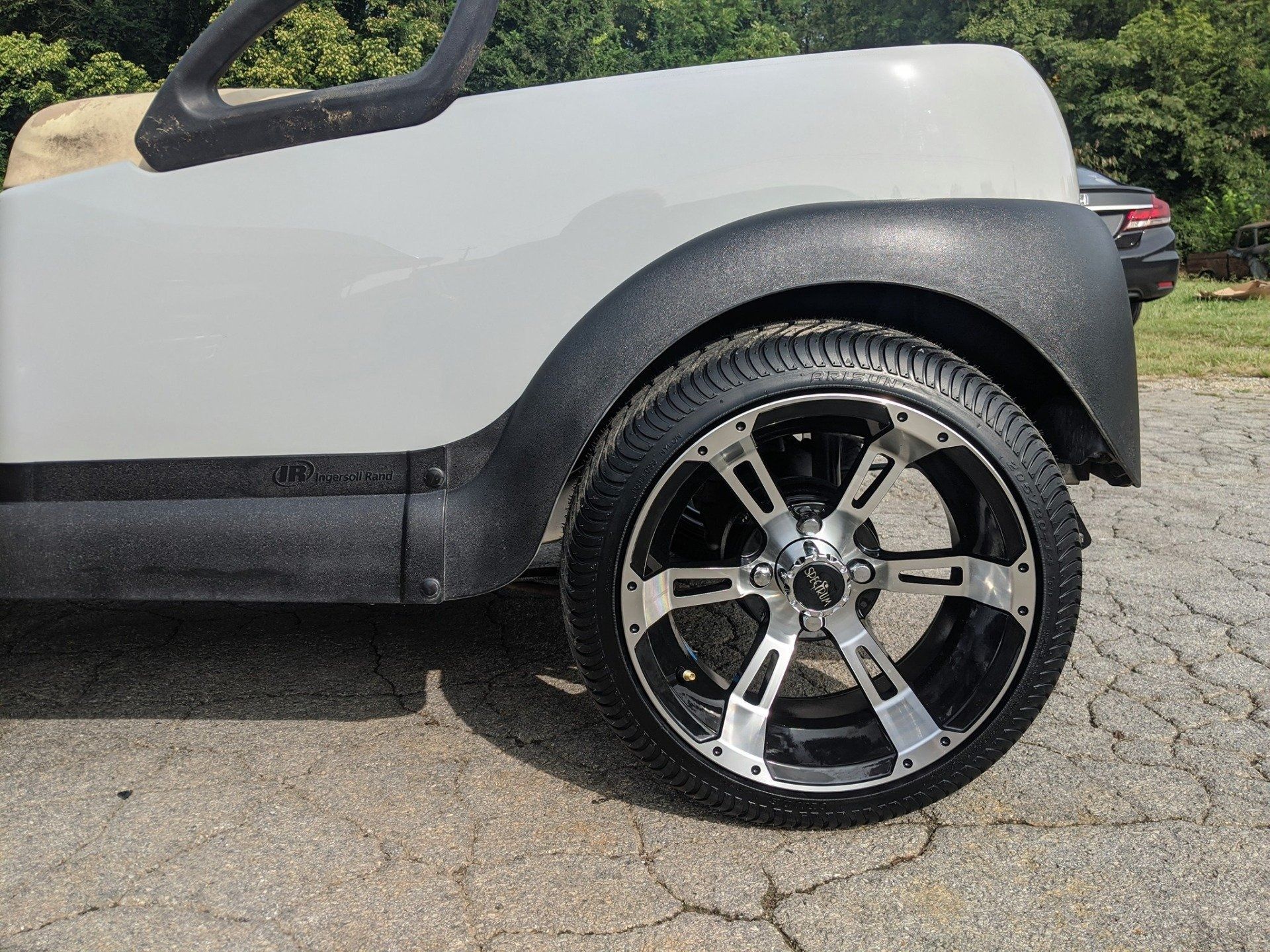 A white golf cart is parked on the side of the road.