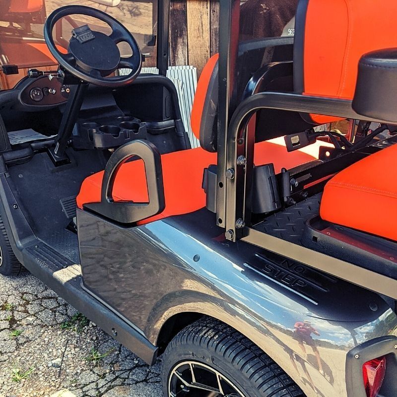 A black golf cart with orange seats and a steering wheel
