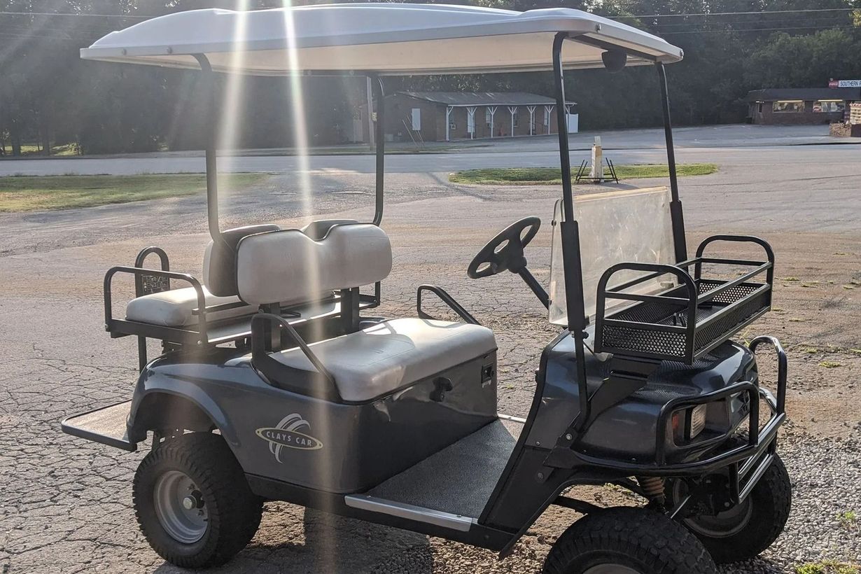 A golf cart is parked in a gravel lot