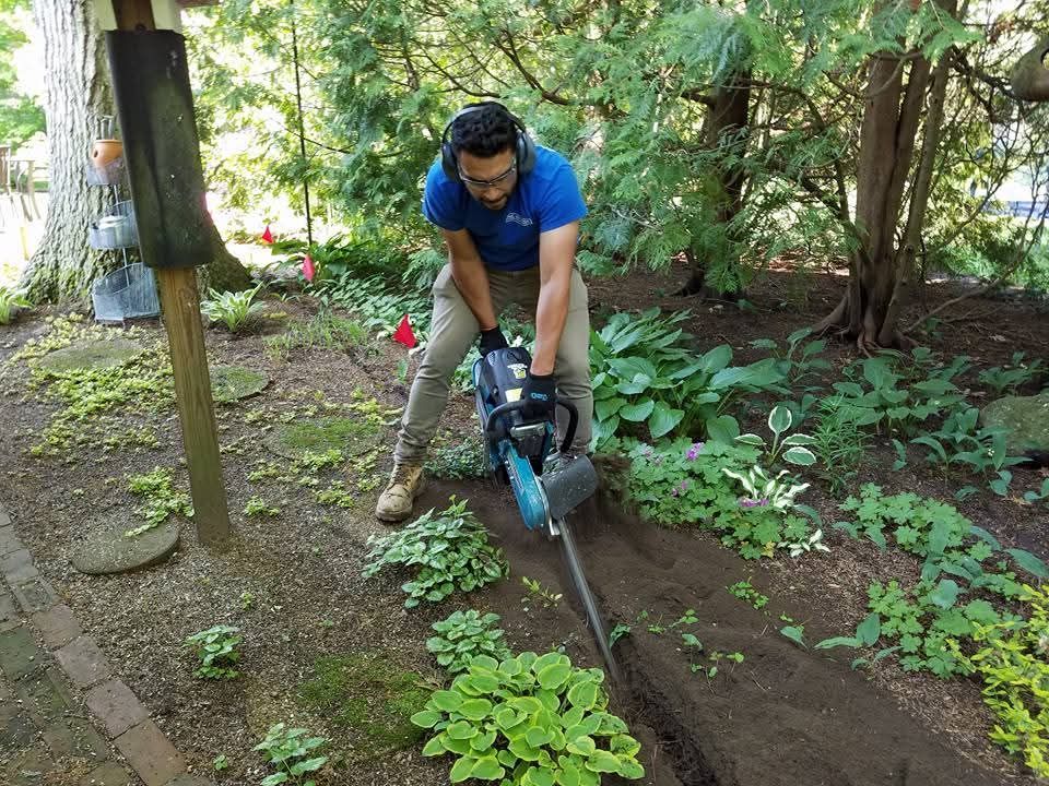 A man is using a chainsaw to dig a hole in the ground.