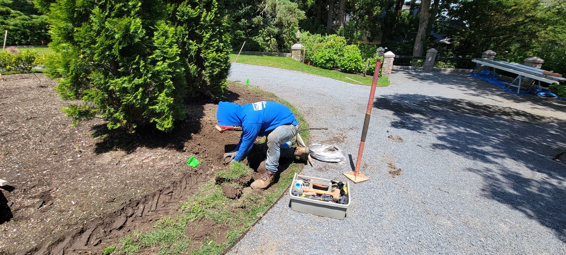 A man is kneeling down in the dirt in a garden.