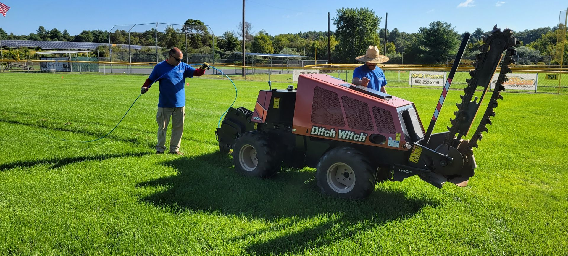 Two men are standing next to a tractor in a grassy field.