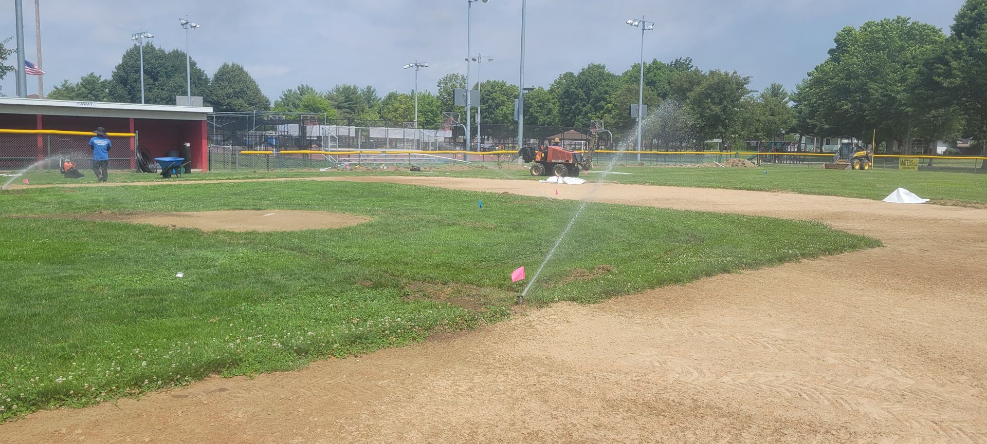 A baseball field with a sprinkler spraying water on the grass