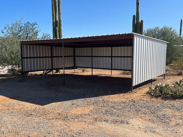 Metal and steel open-sided shed with a dark roof in a desert setting.
