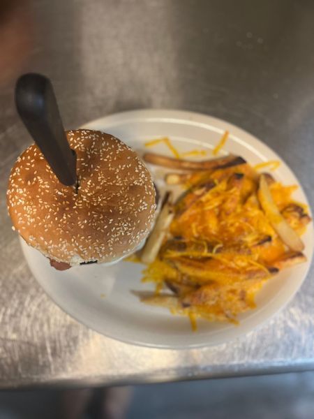 Burger and fries in a white container on a stainless steel counter.