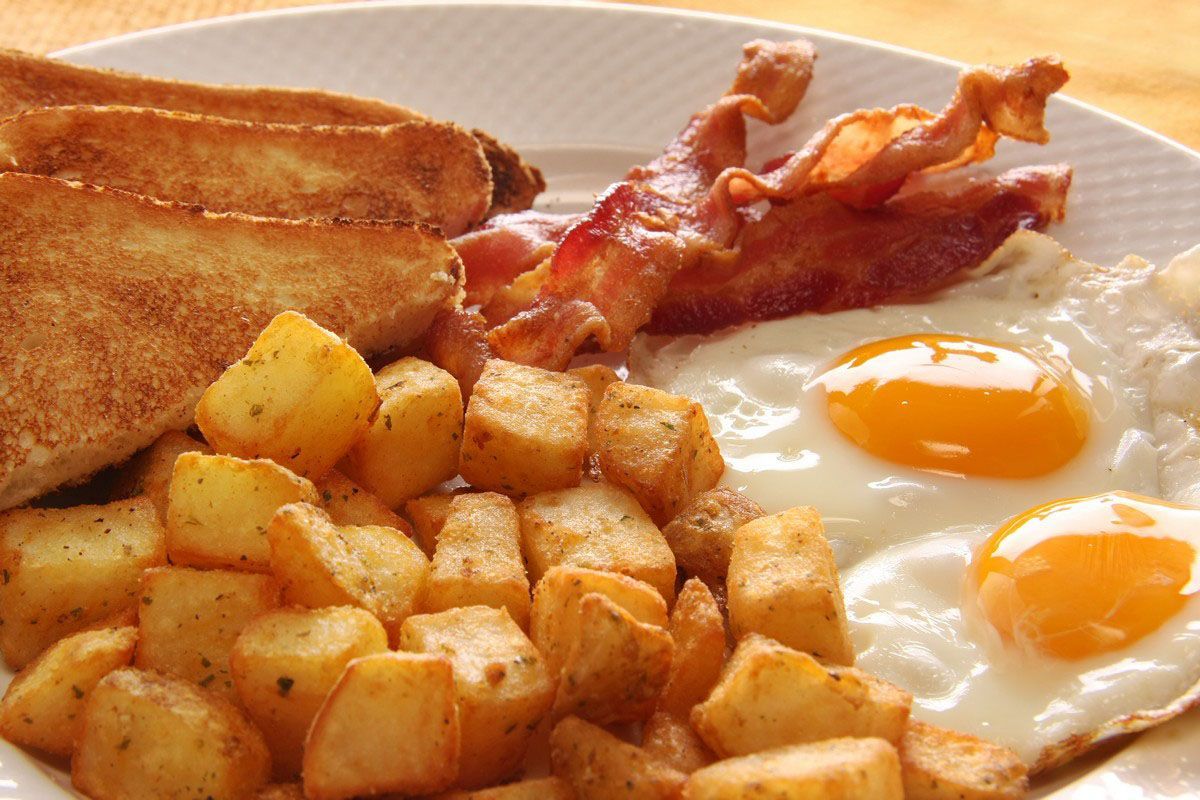 Breakfast plate with eggs, bacon, hash browns, and toast on a white dish