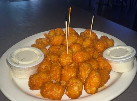 Plate of golden fried bites with two dipping sauces and wooden skewers on a white plate.