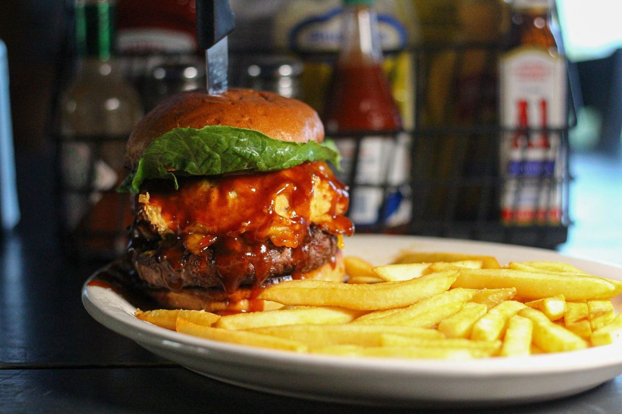 Burger and fries on a white plate, with a toasted bun and green lettuce in a restaurant setting