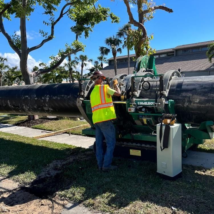 A man in a yellow vest is working on a pipe