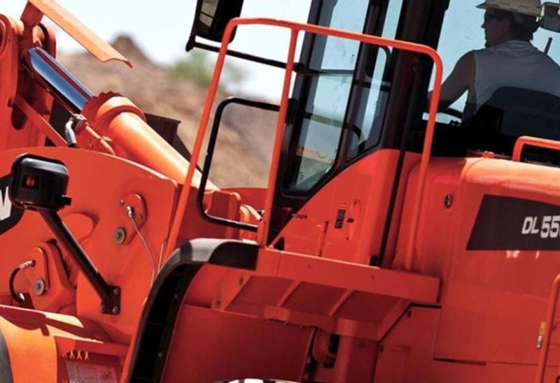 A man in a hard hat is driving an orange dl55 tractor