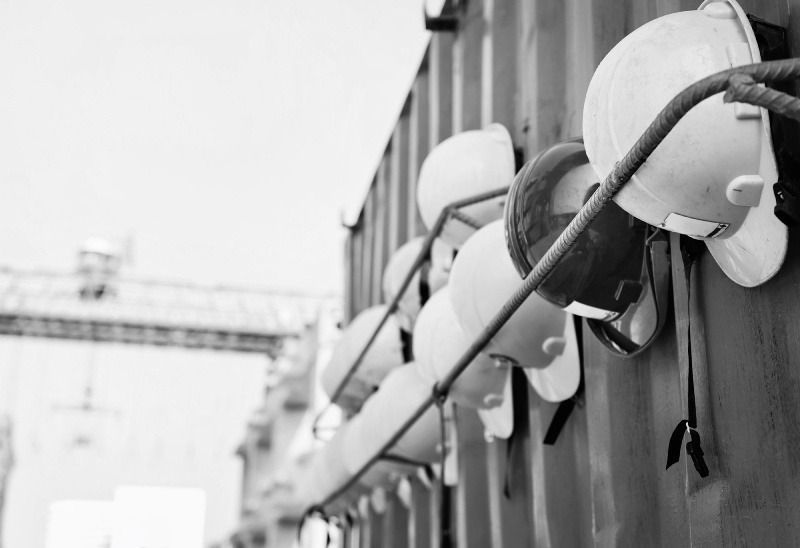 A black and white photo of a row of hard hats hanging on a wall.