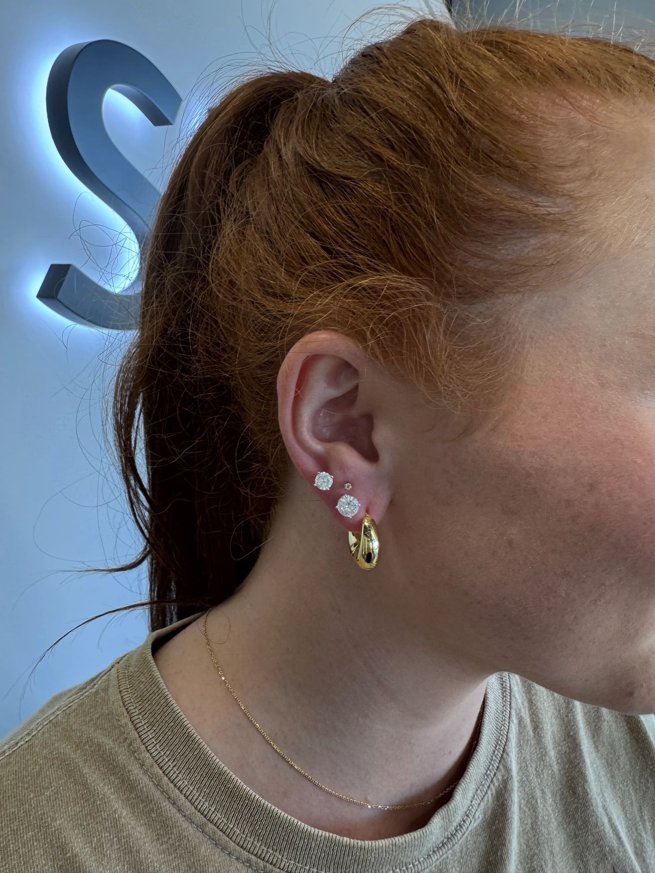 A woman with red hair is wearing earrings and a ponytail.