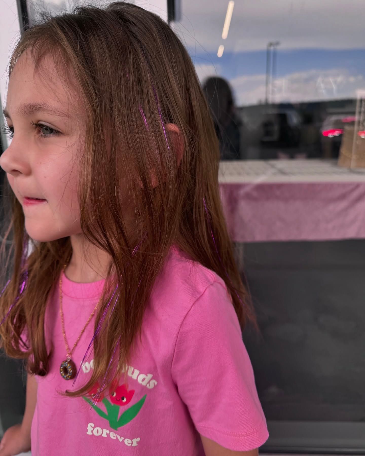 A little girl wearing a pink shirt that says forever