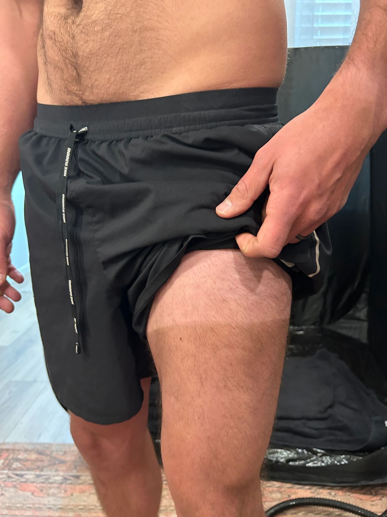 A man without a shirt is wearing black shorts