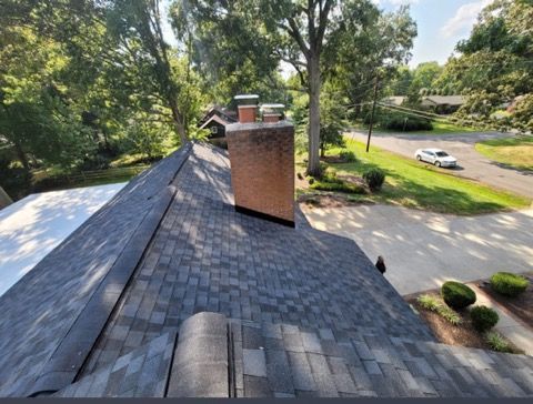 A roof with a chimney on it and a car parked in the driveway.