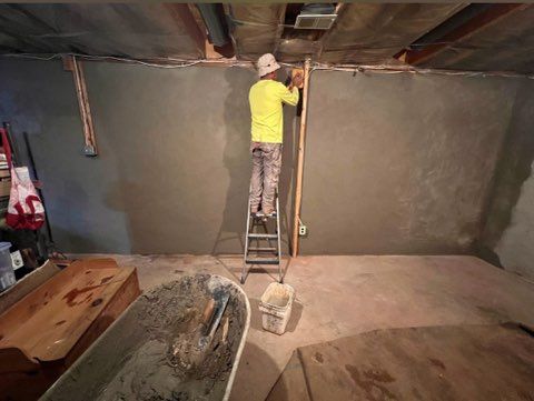 A man is standing on a ladder in a basement.