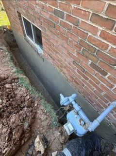 A brick wall with a window and a pipe coming out of it.