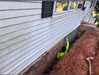 A man is digging a hole in the side of a house