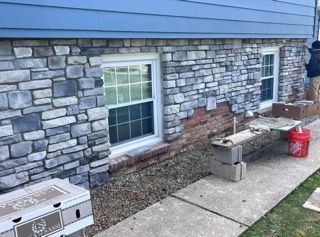 A man is painting a stone wall of a house.