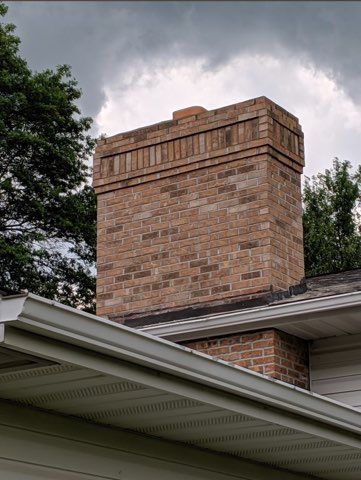A brick chimney is on the roof of a house.