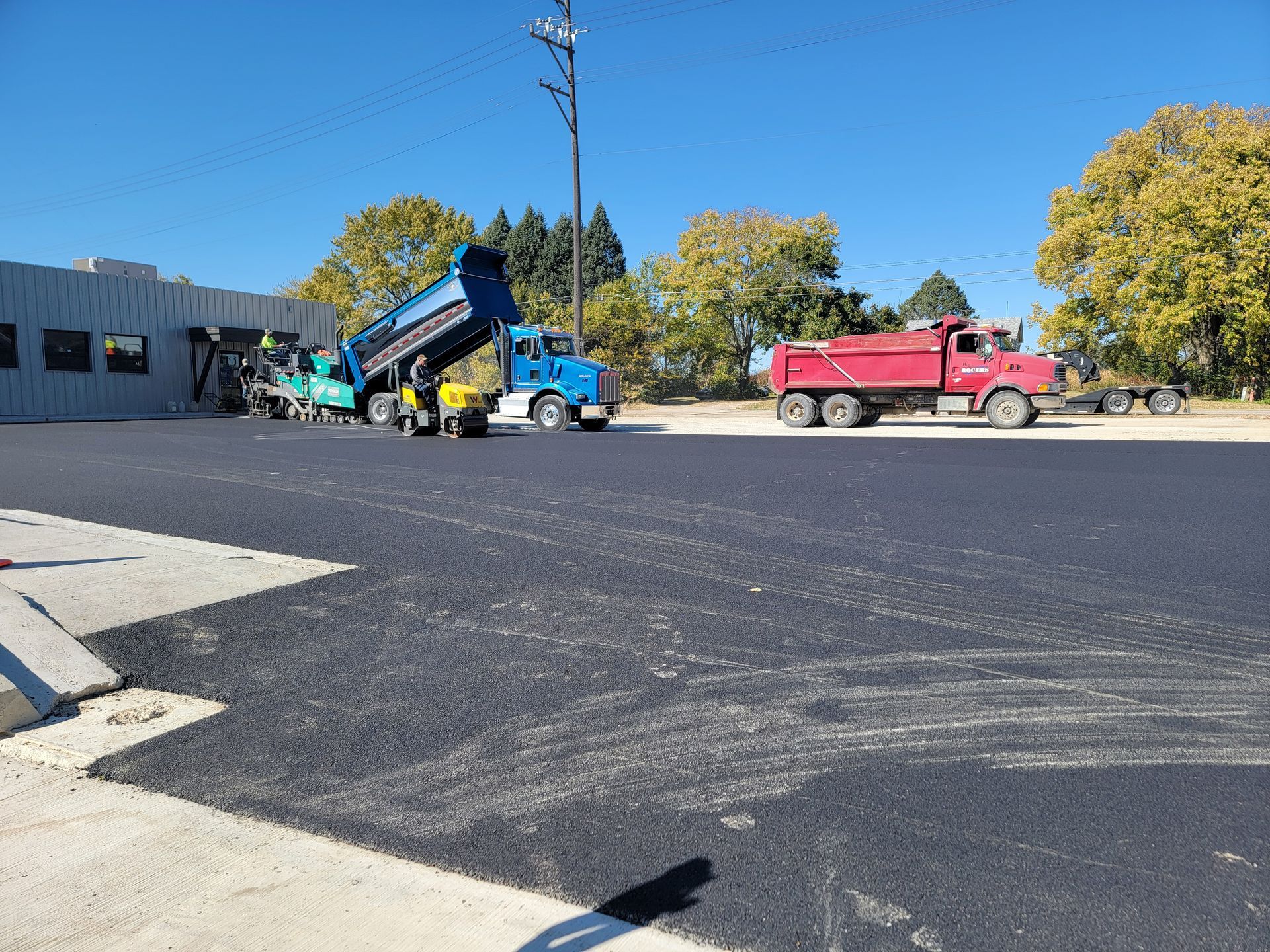 A dump truck is being loaded with asphalt in a parking lot.