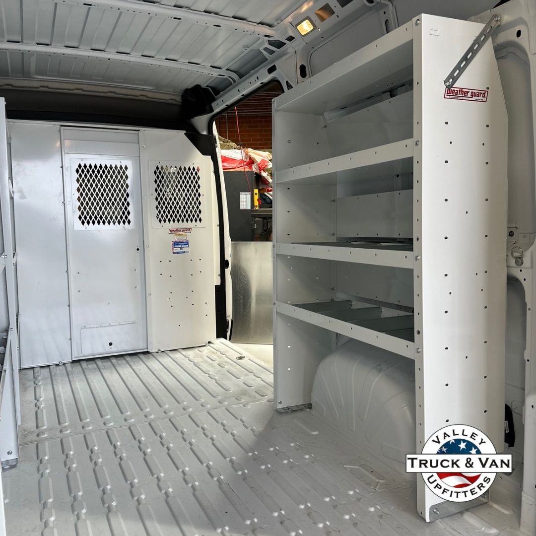 White cargo van interior with shelving, a partition, and a clean floor.