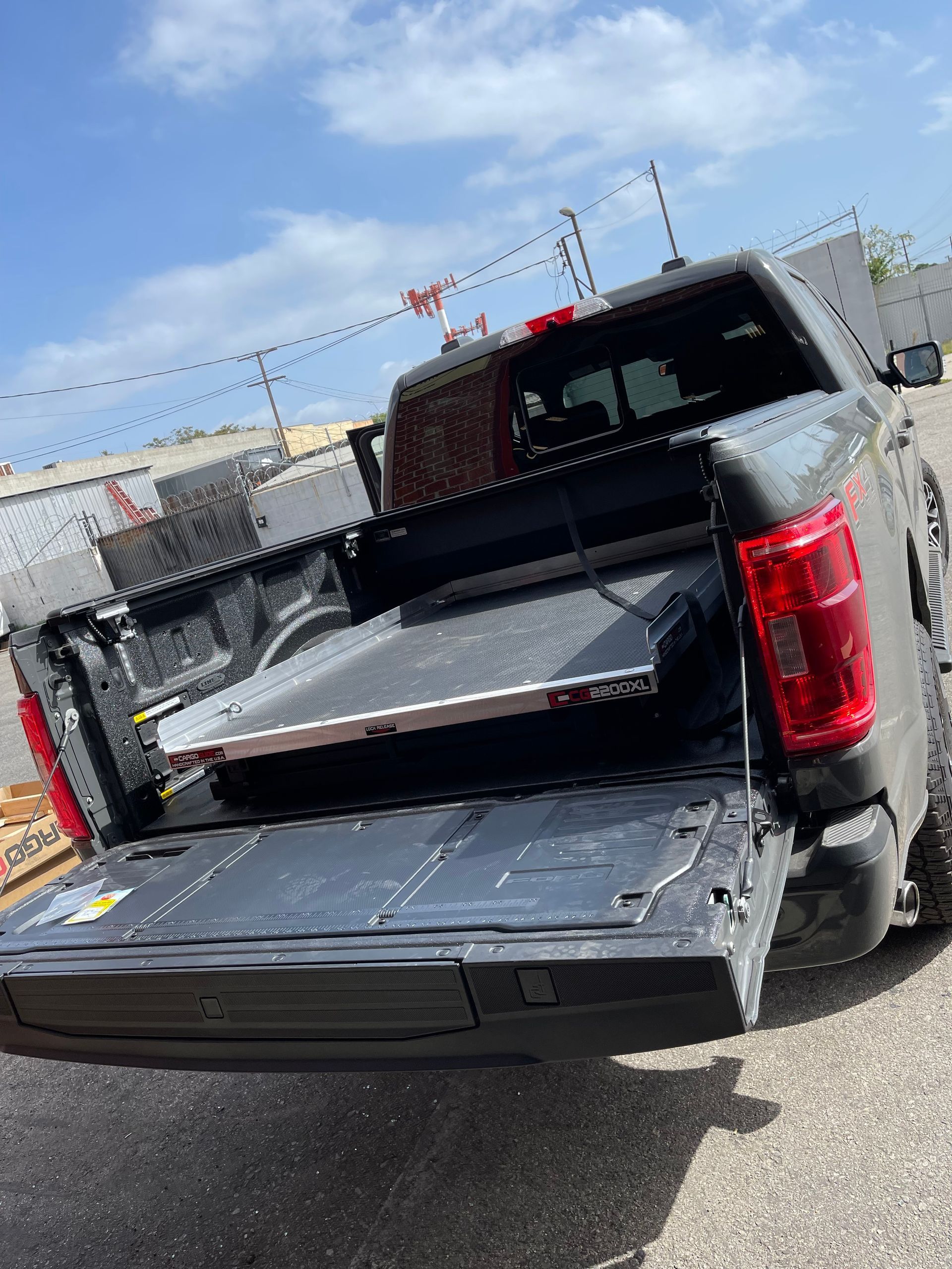 Gray pickup truck parked outdoors with its tailgate down, showing a sliding cargo bed tray.