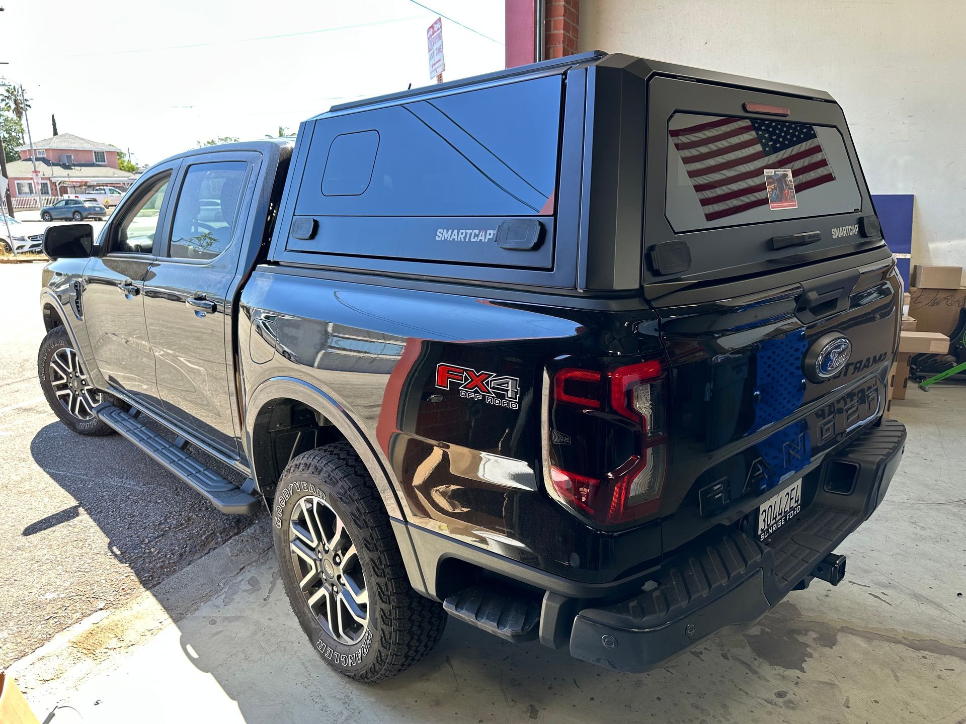 A black Ford truck with a matching canopy shell parked outdoors, showing the rear and side profile.