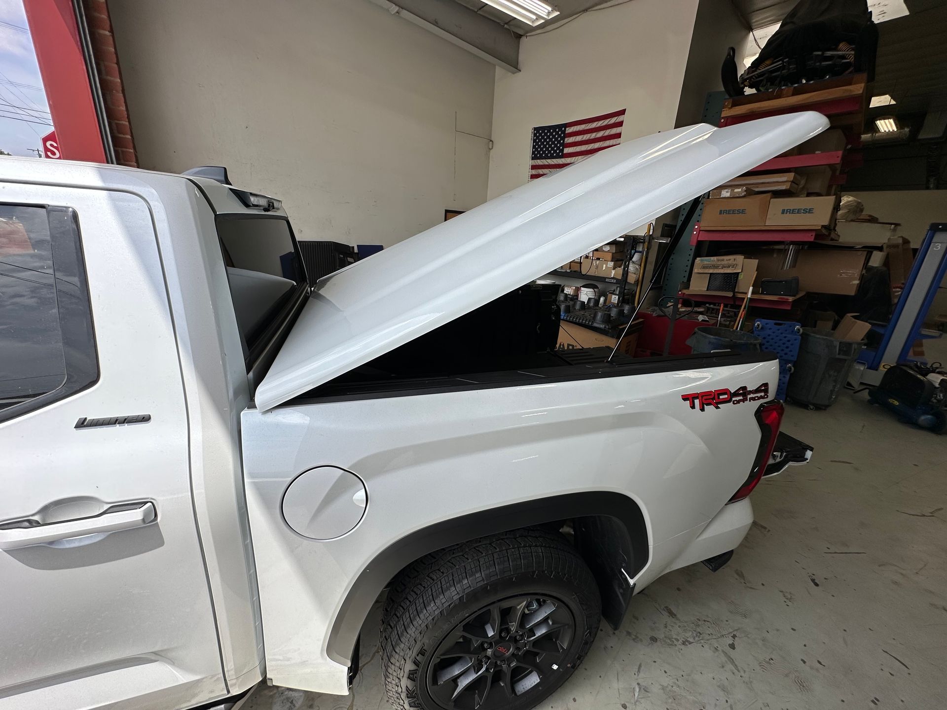 A white pickup truck with a TRD Pro decal parked in a garage with its hard tonneau cover raised.
