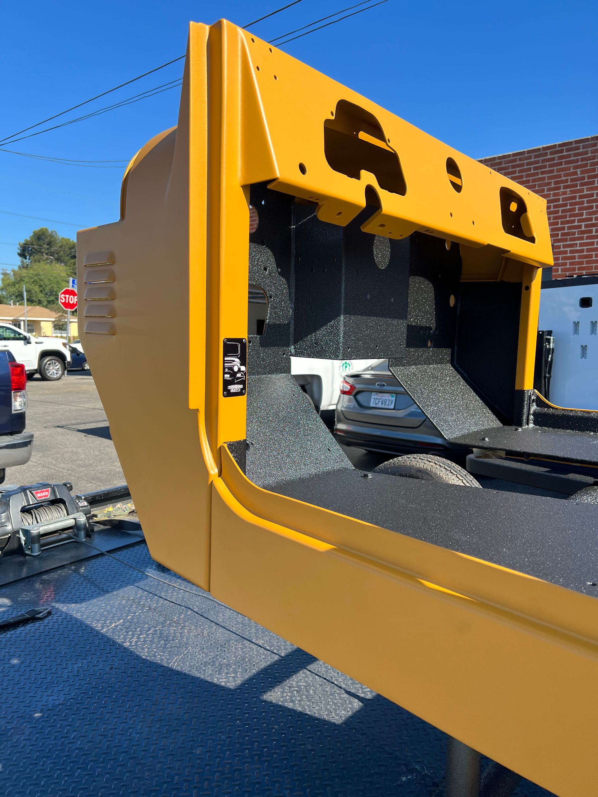 A large, yellow piece of heavy machinery equipment sits outdoors on an asphalt lot on a sunny day.