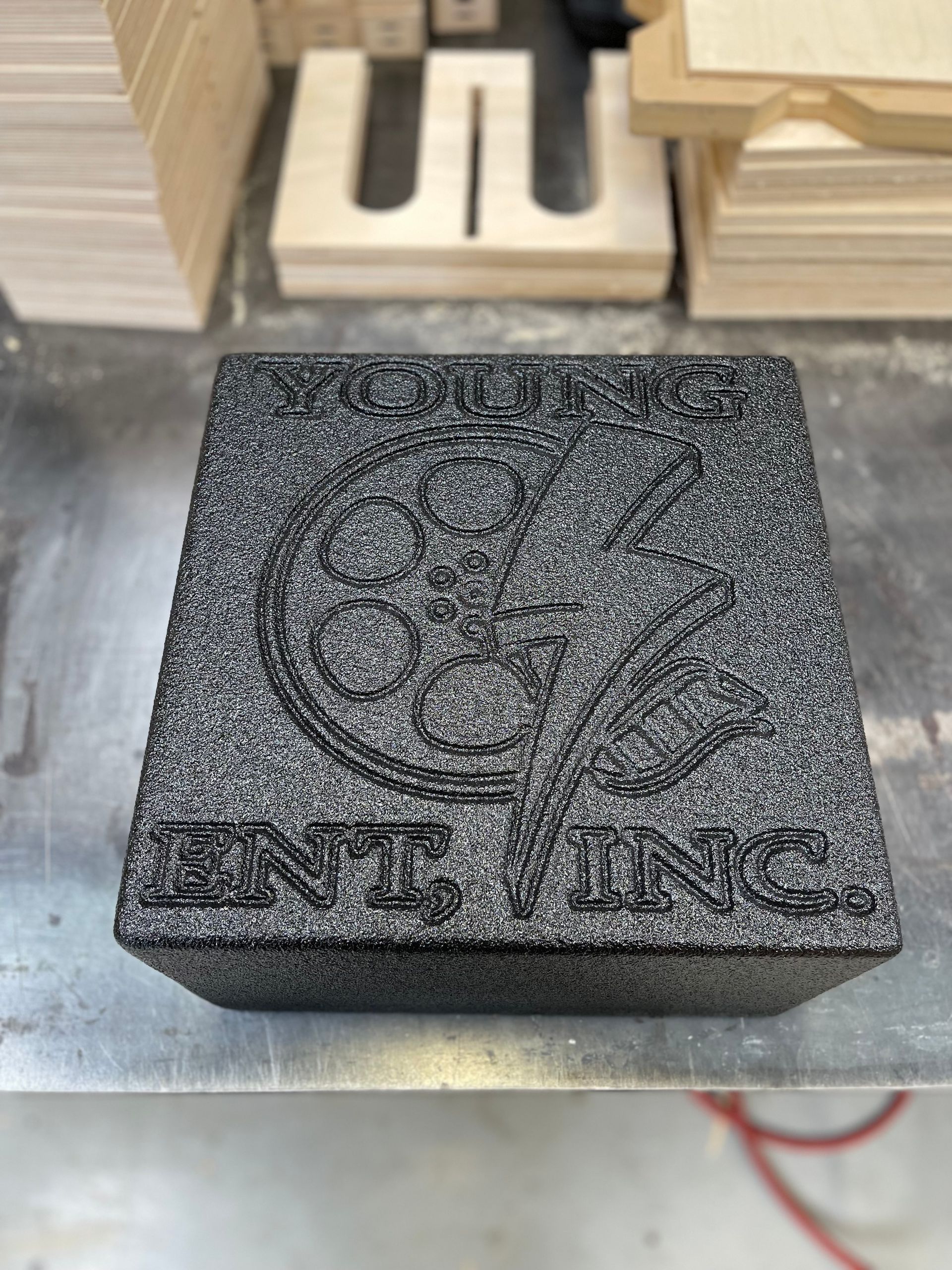 A textured, black stone plaque featuring an engraved film reel logo and the text 