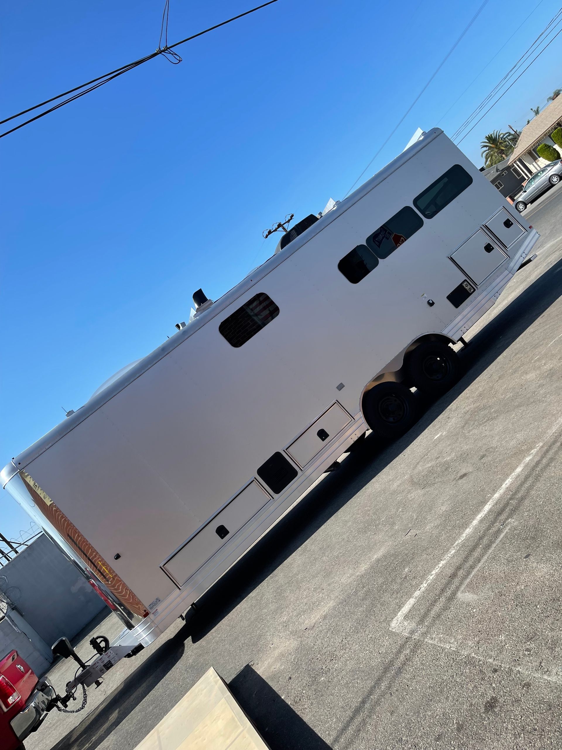 A white travel trailer parked outdoors on a paved lot under a clear blue sky.