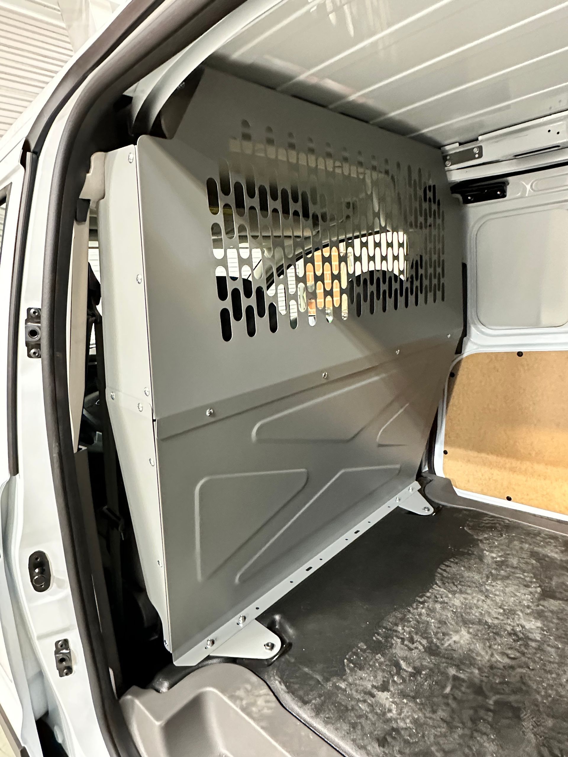 Gray steel cargo partition installed inside a commercial work van, featuring an upper perforated viewing panel.