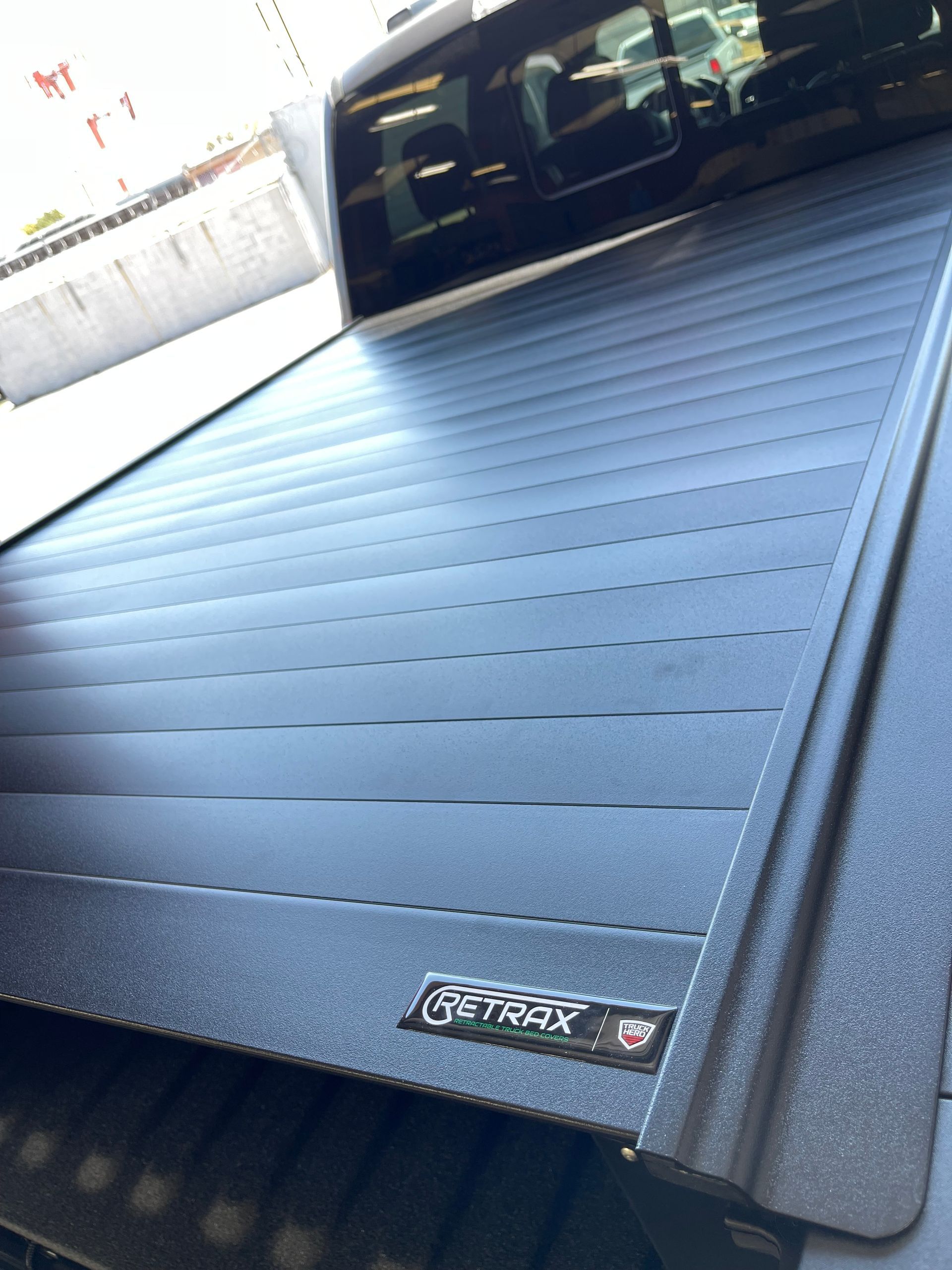 A matte black retractable tonneau cover with a Retrax logo installed on the bed of a pickup truck.
