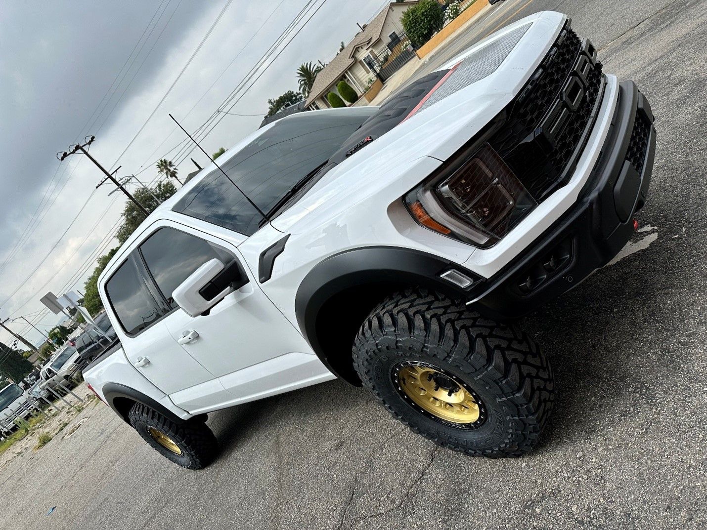 White lifted pickup truck with off-road tires parked at an angle in a lot