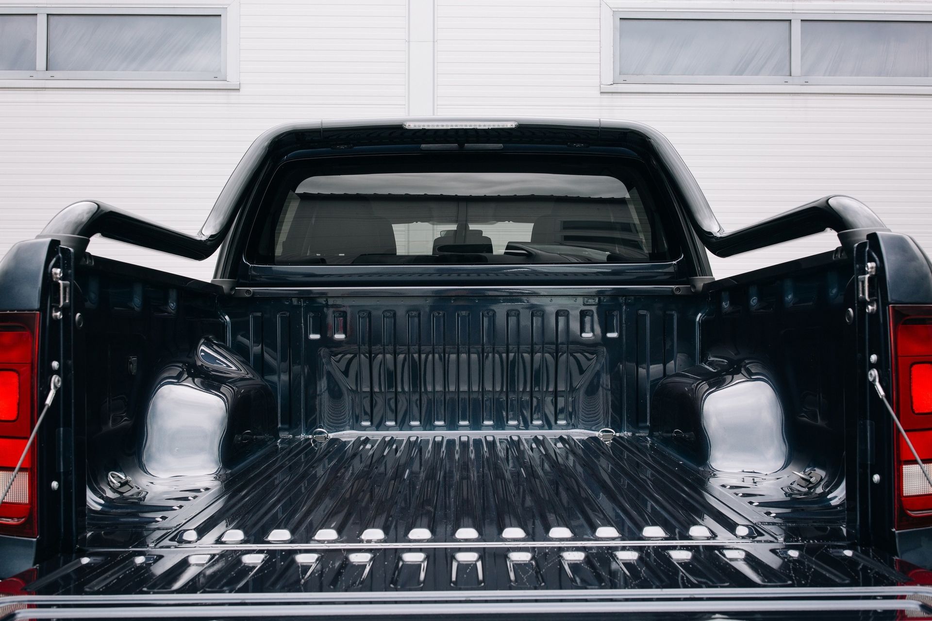 Empty dark pickup truck bed with side rails and tail lights.