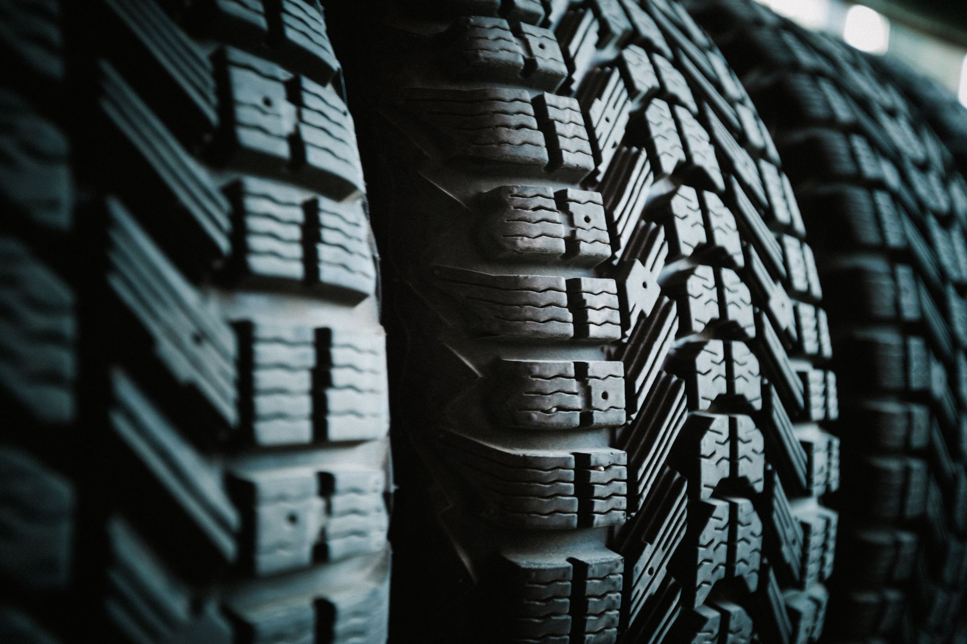 Close-up of a row of black, ridged tires, likely winter or all-weather.