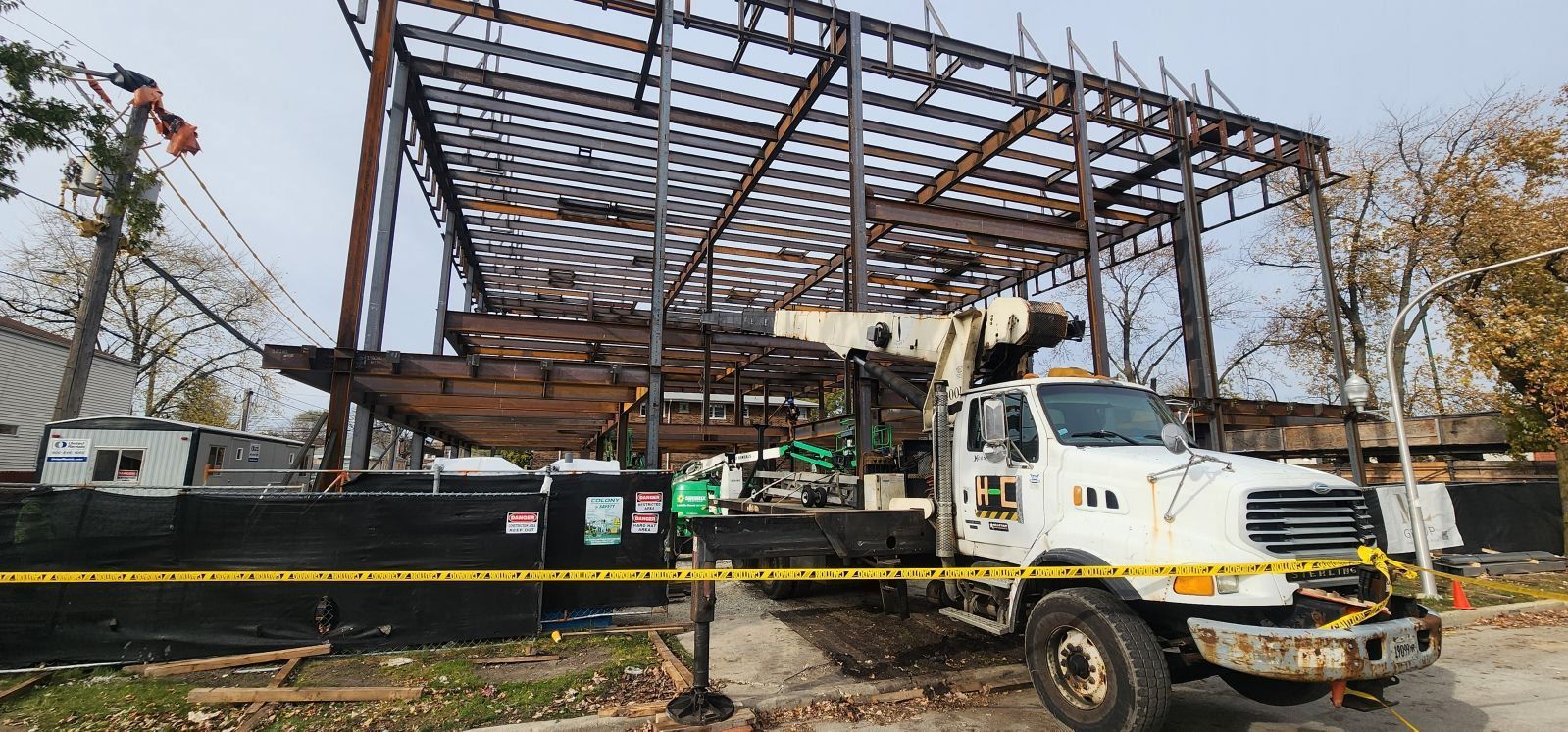 A white truck is parked in front of a building under construction.
