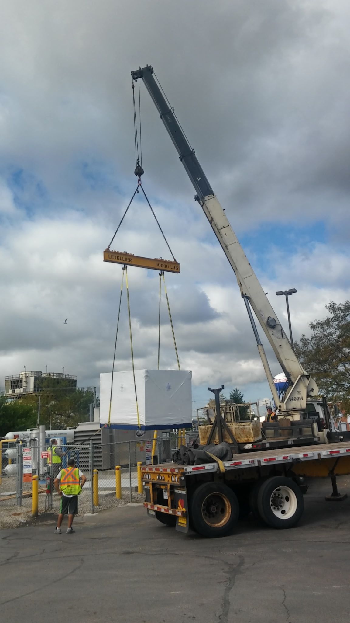 A crane is lifting a large white box on top of a truck