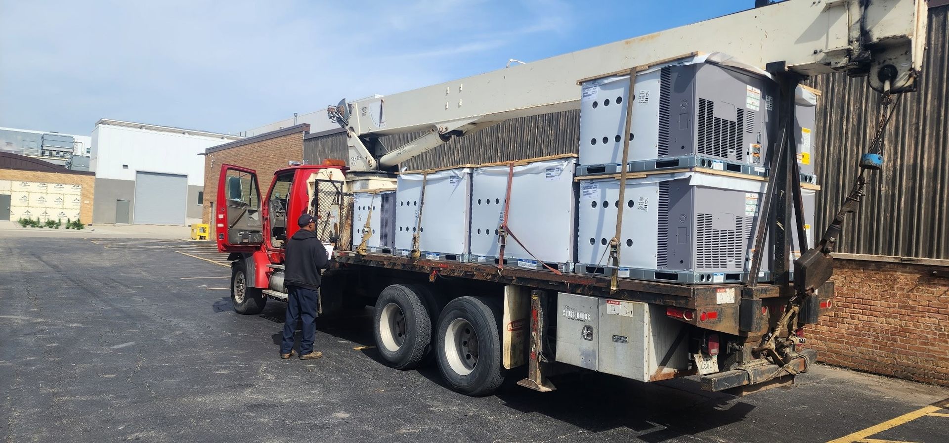 A man is standing next to a truck loaded with crates in a parking lot.