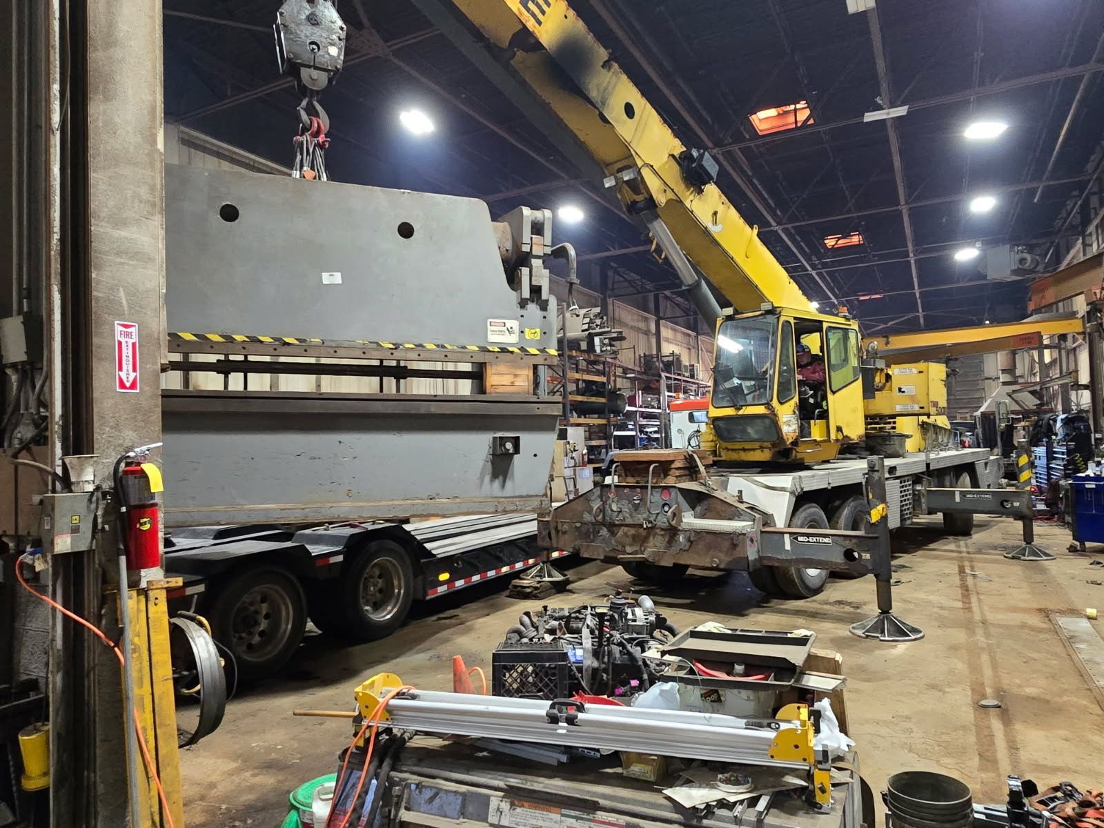 A crane is lifting a large piece of metal in a warehouse.
