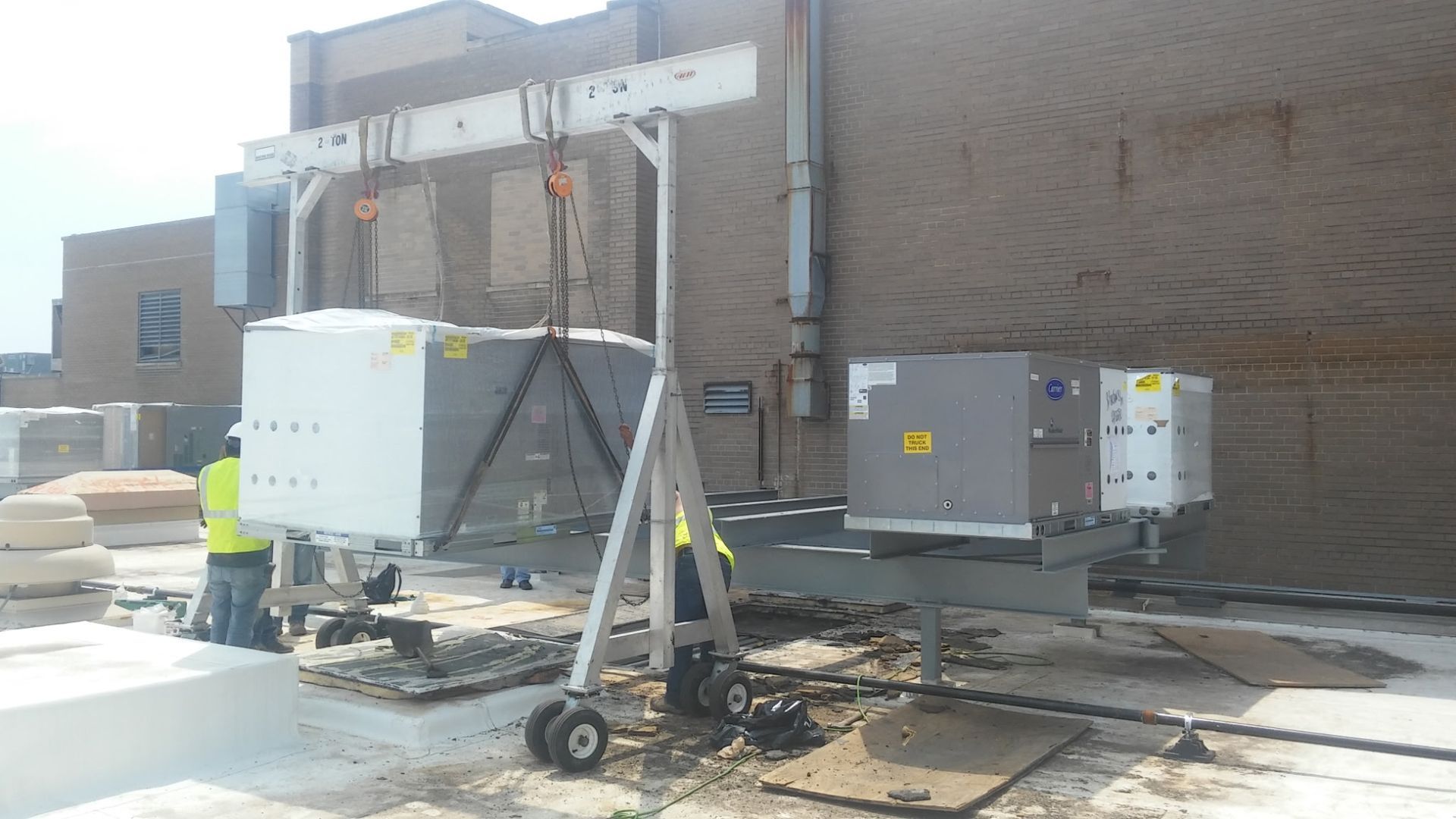 A man is standing next to a machine that is being lifted by a crane.